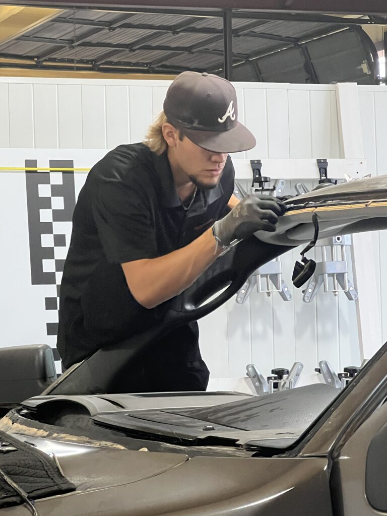 A man working on the hood of a car.