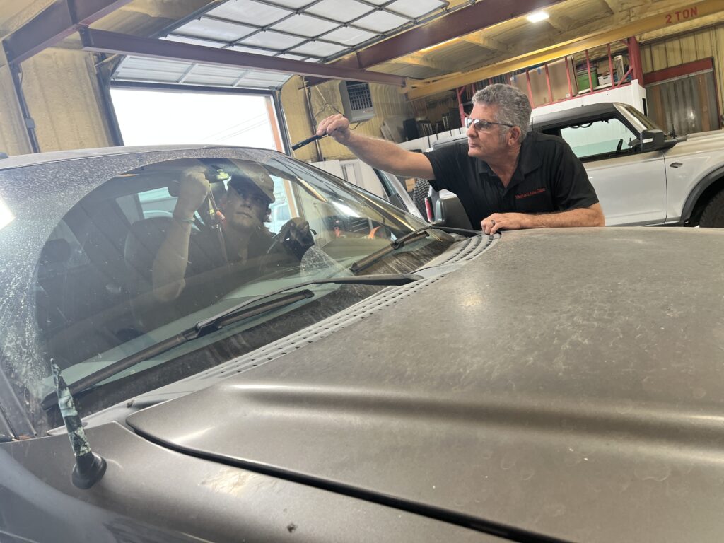 A man looking at the windshield of a car.
