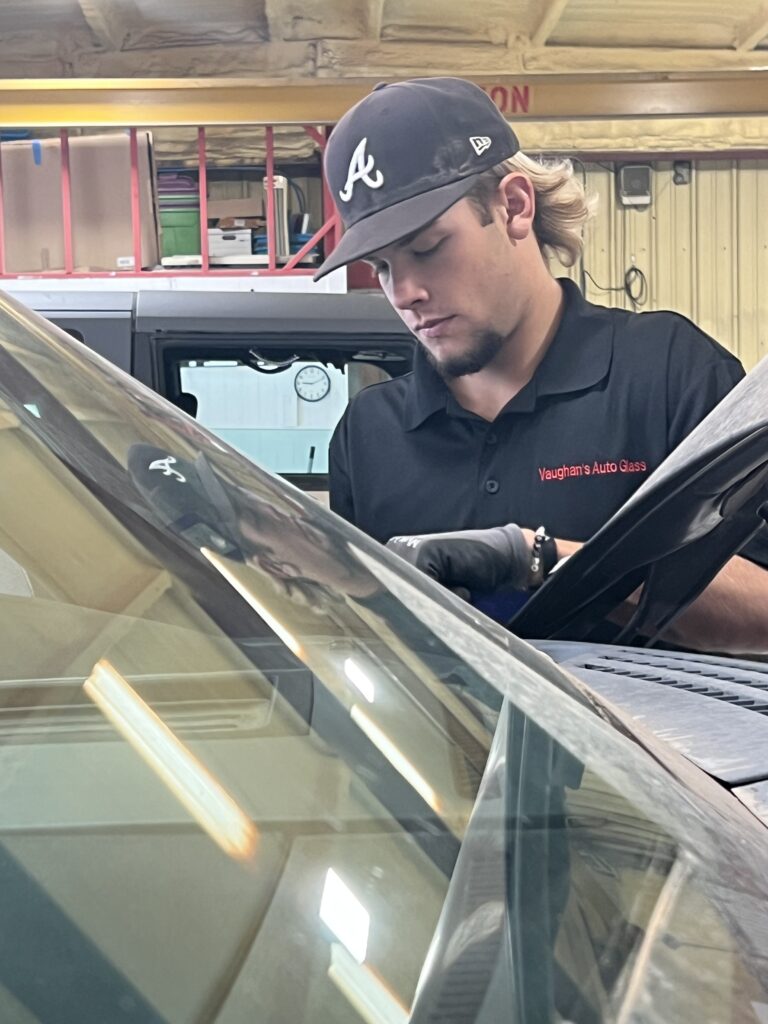 A man working on the windshield of a car.